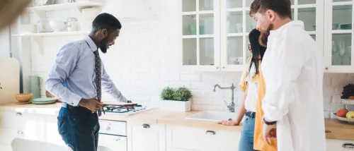Landlord inspecting a new kitchen along with renters in a bright apartment, inspecting the stove as part of an apartment inspection.