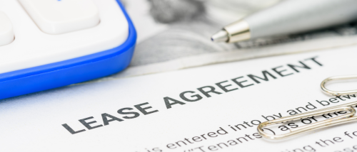 A document outlining a lease agreement, surrounded by paper clips, a calculator, and a pen.