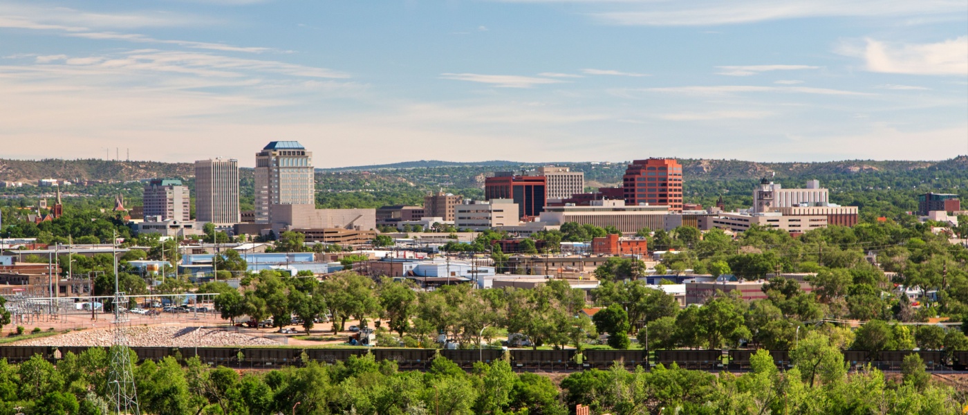 Downtown Colorado Springs cityscape with mountains in the background on a sunny day, illustrating the cost of living in Colorado Springs.