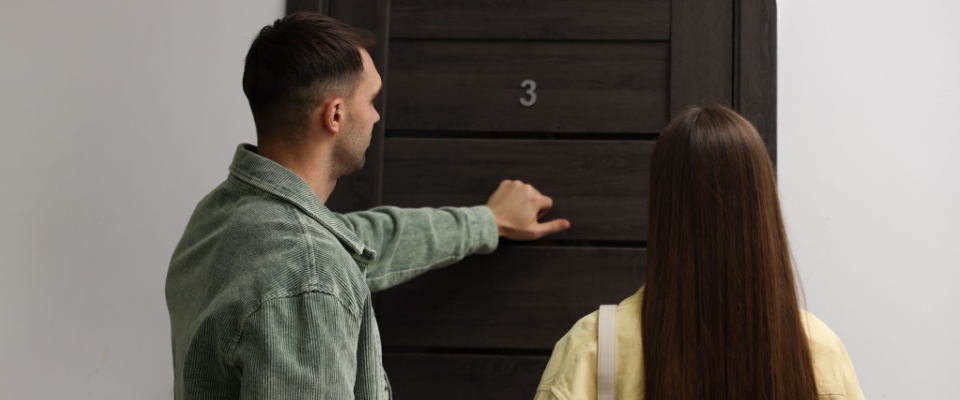 Couple knocking on neighbors' door in order to let them know about their Thanksgiving celebration, showcasing one of the tenents of apartment etiquette.