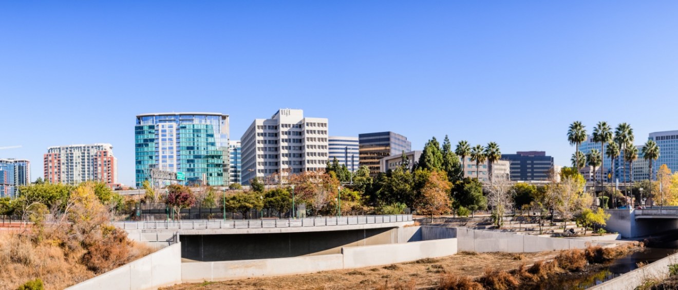 Panoramic view of San Jose's downtown skyline as seen from the shoreline of Guadalupe River on a sunny fall day to illustrate questions to ask before renting an apartment in San Jose, CA.