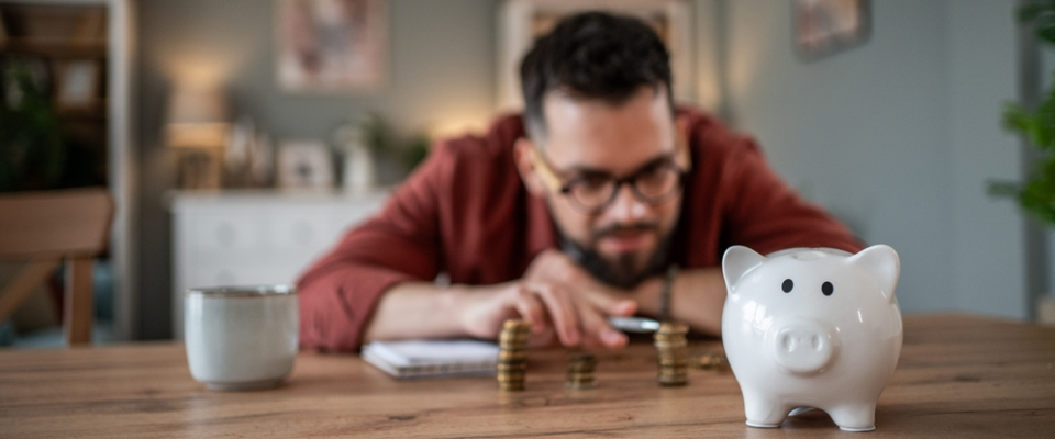 A renter calculating savings with a piggy bank and stacked coins — illustrating security deposits and budgeting for apartments in Grand Rapids, MI.
