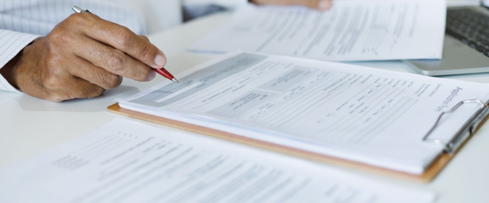 Man reviewing documents and contracts at his office desk, representing attention to detail and paperwork preparation for a first-time renter.