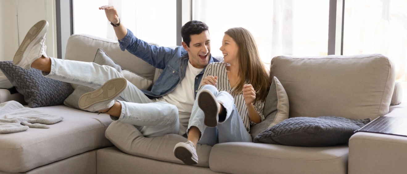 A happy renter couple relaxing on a couch after receiving their rental pre-approval, celebrating the good news about being pre-approved for a rental property.