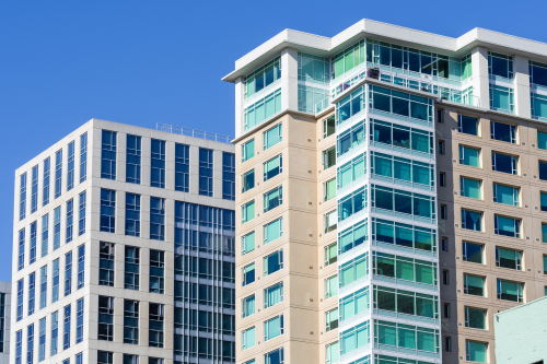 Exterior view of multifamily residential building, next to an office building; rental market outlook 2025