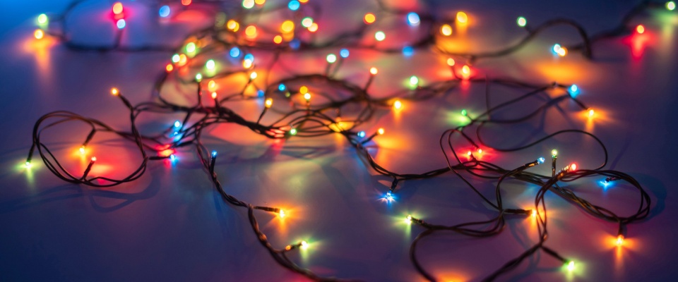 Colorful holiday string lights spread out on a surface, illustrating holiday safety tips for checking decorations to prevent electrical hazards.