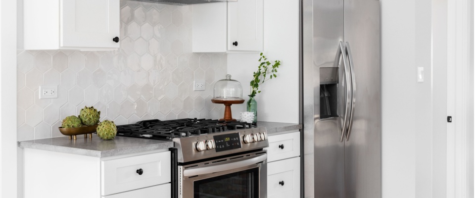 Clean kitchen with a stainless-steel refrigerator and gas stove, showing the value of routine kitchen appliance maintenance for safety and performance.
