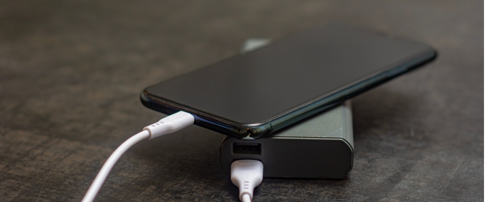 Smartphone connected to a portable power bank, a crucial device to have in your apartment during a power outage for communication and safety.
