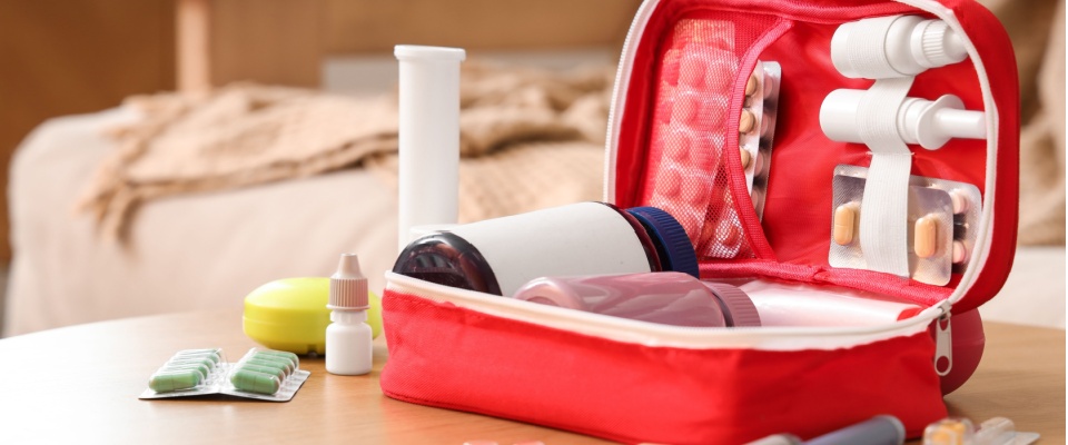 Open first-aid kit with medicines and essentials on a table, showing important items to have in your apartment during a power outage.