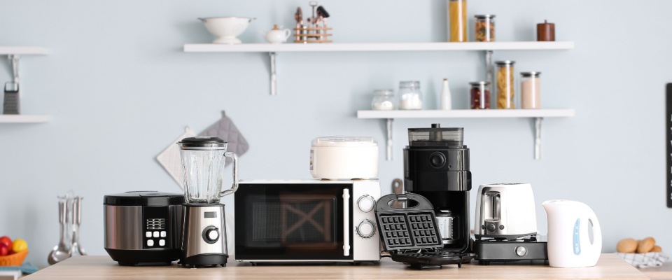 Assorted small appliances like a blender, waffle maker, and air fryer on a countertop, highlighting the importance of regular appliance maintenance.
