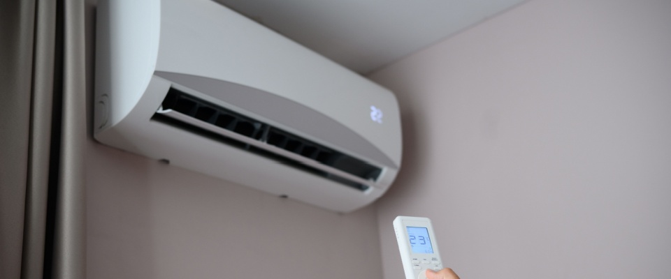 Man adjusting an air conditioner with a remote, setting the temperature to 22°C, reflecting energy-efficient comfort in apartments in Tampa.