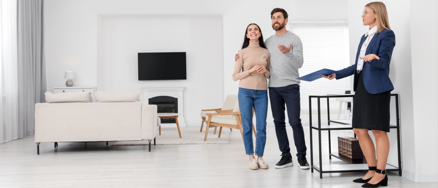 Real estate agent giving a couple a tour of a new apartment, highlighting the space and features.