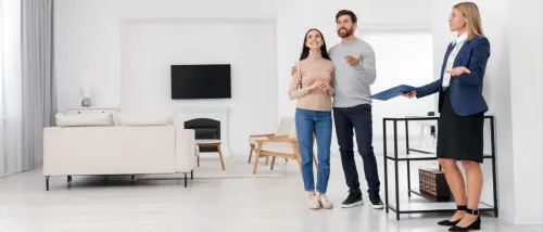 Real estate agent giving a couple a tour of a new apartment, highlighting the space and features.