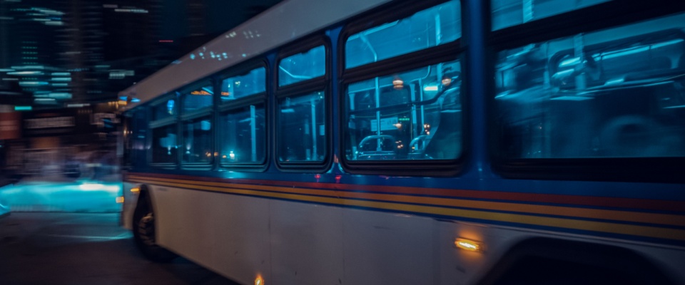 The side of a bus in traffic at night to illustrate public transport in Denver.