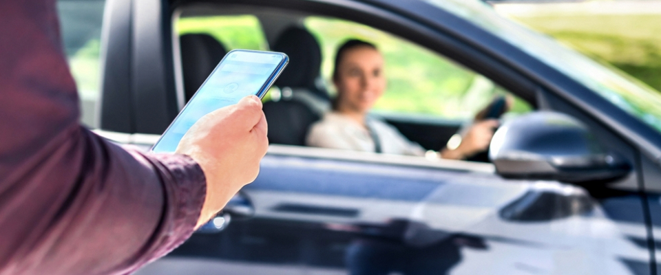 Person using a smartphone app to access a car-sharing vehicle, showing a flexible transportation option for renters who need a car without owning one.