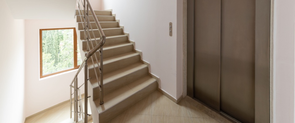 Interior of a modern building showing the elevator and staircase, suitable for an apartment tour.