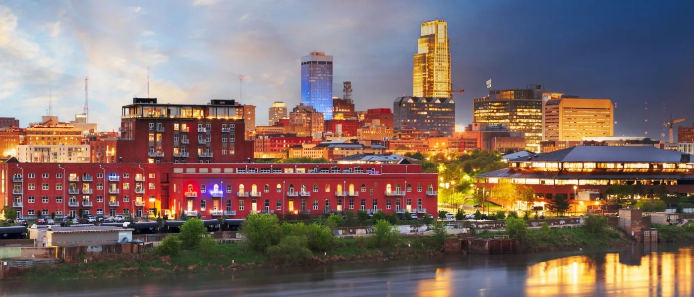 Nighttime view of Omaha’s downtown skyline reflecting on the Missouri River, representing the cost of living in Omaha.