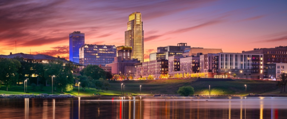 Downtown Omaha skyline reflected on the water at autumn sunset, illustrating the cost of living in Omaha.