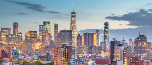 Panoramic view of the Manhattan skyline at sunset, showcasing high-rise buildings and city lights—illustrating what renters can expect when considering the cost of living in Manhattan, NY.