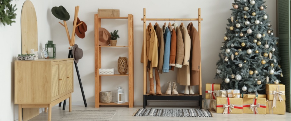 Apartment hunt concept shown through a cozy hallway interior with a Christmas tree, coat rack, and drawers, highlighting a welcoming apartment space.