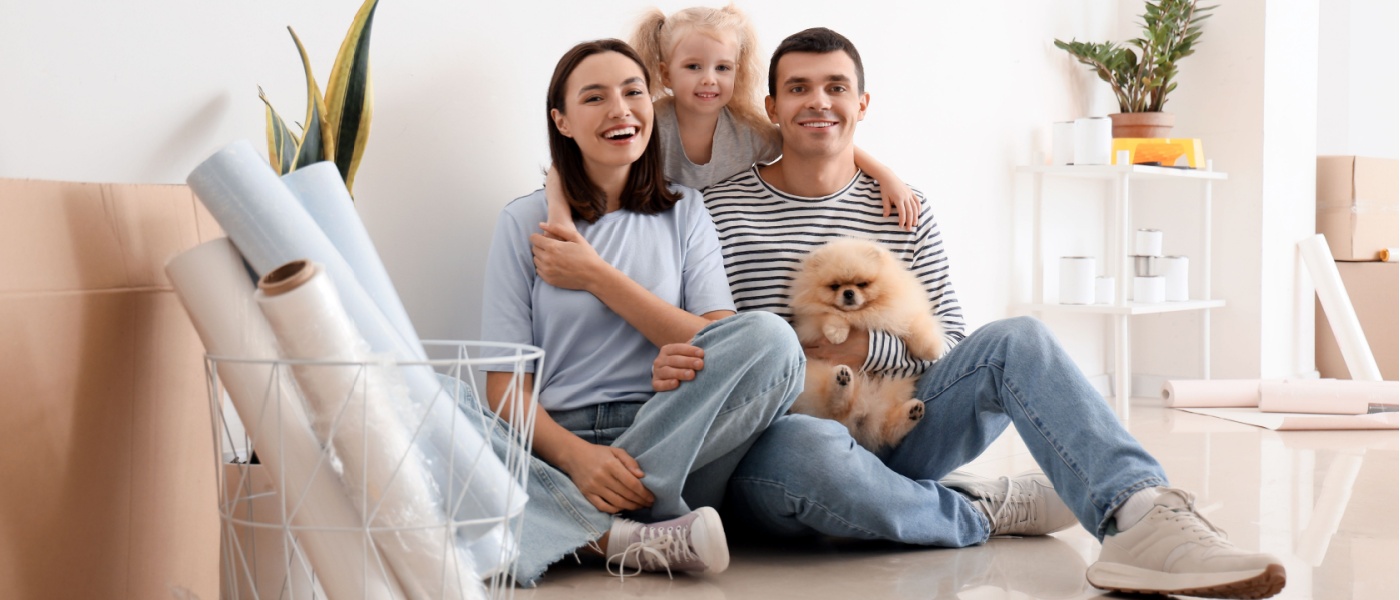 A happy family hugging while sitting on the floor of their apartment to illustrate how to find apartments for families.