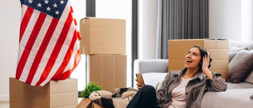 Young person sitting among moving boxes, smiling while listening to headphones, symbolizing key rental trends for 2025 and what renters should know as we head into the next year.