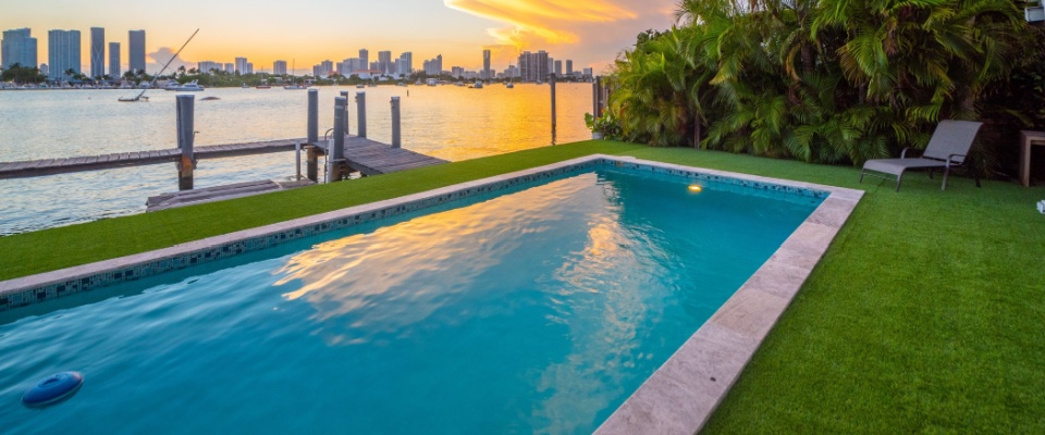 Scenic shoreline with palm trees and bright coastal buildings, described in a way that contrasts with the lifestyle of apartments in Tampa.