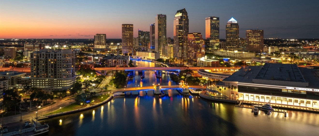 Downtown Tampa skyline at sunset with illuminated high-rise buildings and bridge traffic, representing apartments in Tampa.