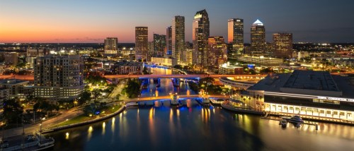 Downtown Tampa skyline at sunset with illuminated high-rise buildings and bridge traffic, representing apartments in Tampa.
