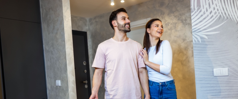 Young couple arriving at an apartment with their luggage for a vacation, capturing the excitement and anticipation of an apartment hunt.
