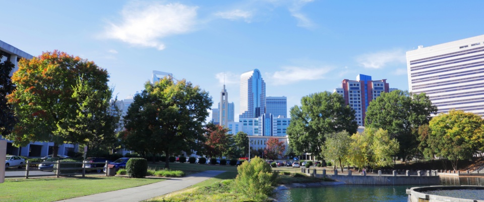 The skyline in downtown Charlotte, NC from a park on a sunny spring day to illustrate the cost of living in Charlotte, NC.