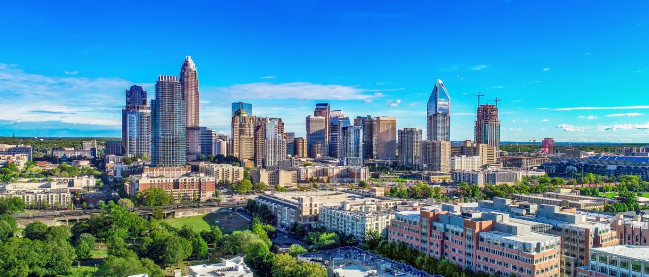 Aerial view of the skyline in Charlotte, NC, with the blue sky as the background to illustrate the cost of living in Charlotte.