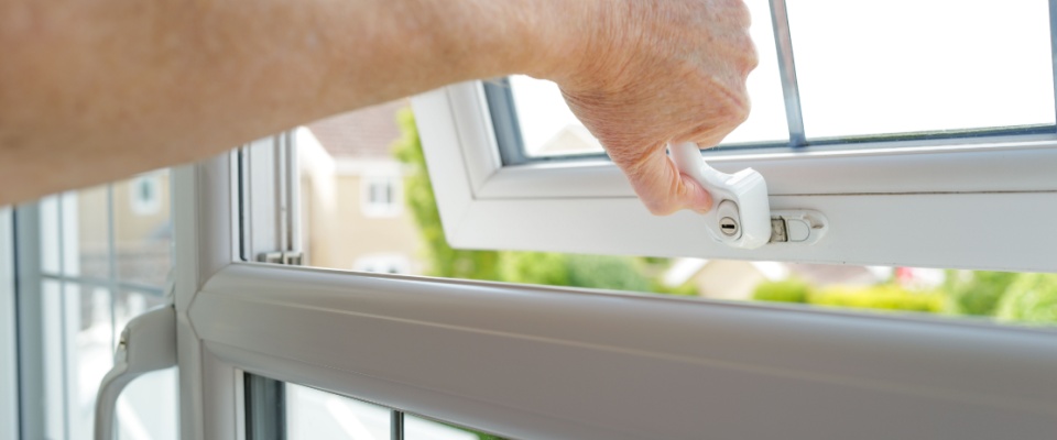 Close-up of a hand opening a window to illustrate secure locks during a winter apartment tour.