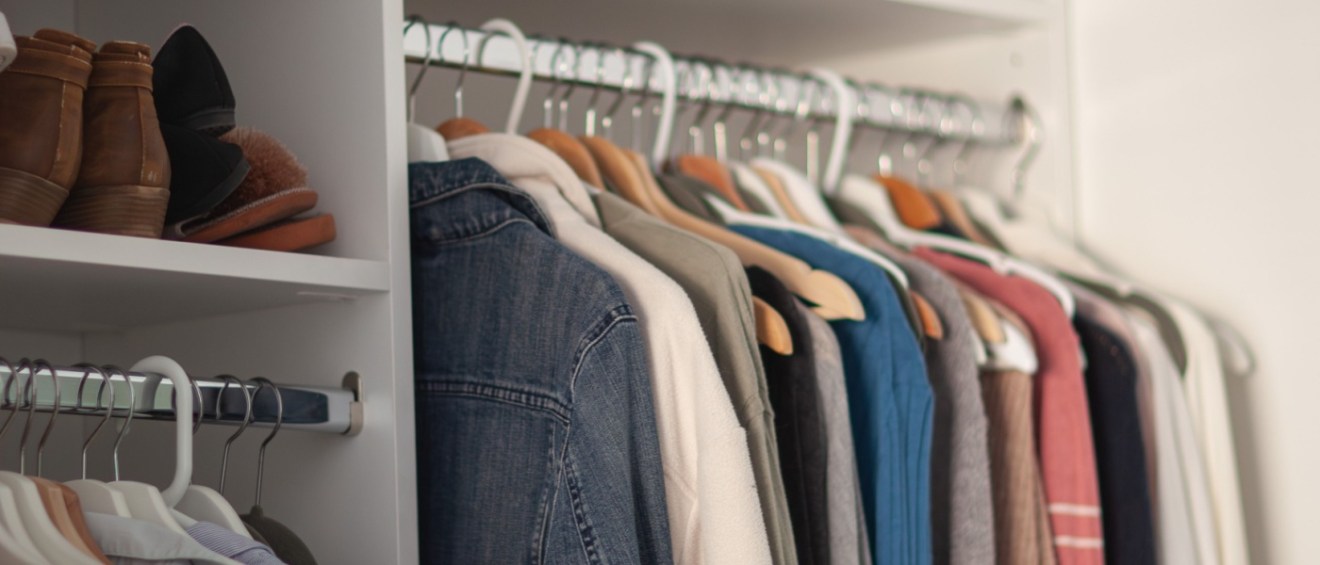 Clean, minimalist closet with coordinated hangers, folded clothes, and shelves, highlighting modern small closet organization ideas for a tidy look.