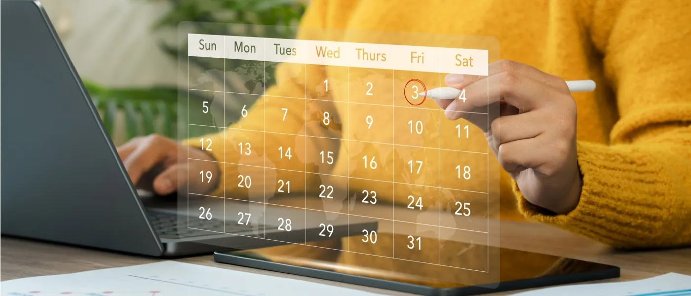 A businesswoman using a pen to mark a virtual calendar in front of a computer to illustrate a lease renewal timeline.
