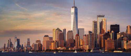 New apartments in Manhattan showcased by the New York City skyline glowing at sunset, with iconic skyscrapers lit by the fading evening light.