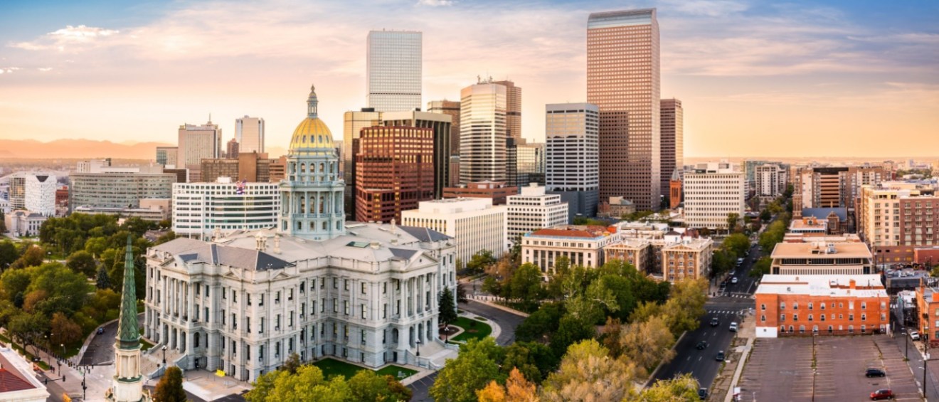 New apartments in Denver shown in an aerial sunset view of the Colorado State Capitol and downtown Denver skyline, with modern buildings and city lights across the urban landscape.