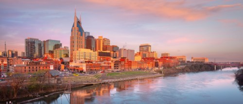 New apartments in Nashville featured in a sunrise view of the downtown Nashville skyline, reflected along the Cumberland River with modern buildings and a growing urban landscape.
