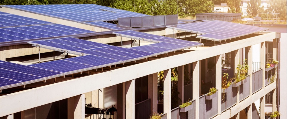 Apartment building rooftop covered with solar panels, showcasing renewable electricity solutions for multi-unit residential properties.