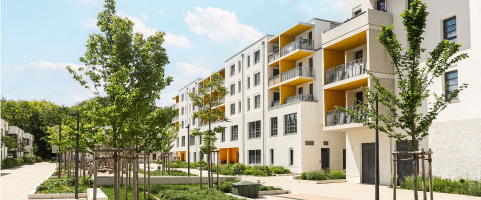 Sustainable apartment complex with green landscaping and balconies, representing communities powered by renewable electricity.