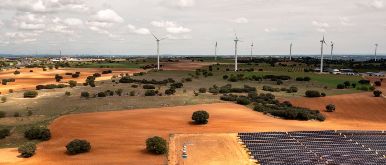 Wind turbines and solar panels across open farmland, highlighting large-scale renewable electricity production from wind and solar energy.