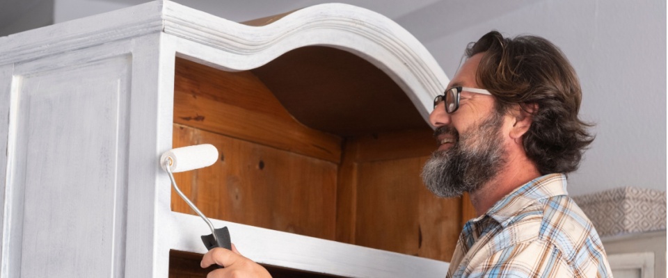 Man painting an old cabinet to give it new life as stylish upcycled furniture.
