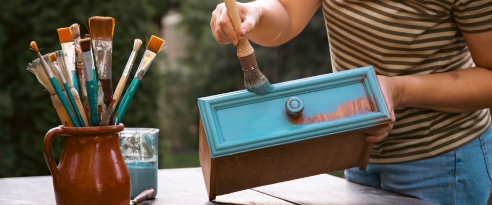 Applying fresh paint to a drawer during a creative upcycled furniture makeover project.