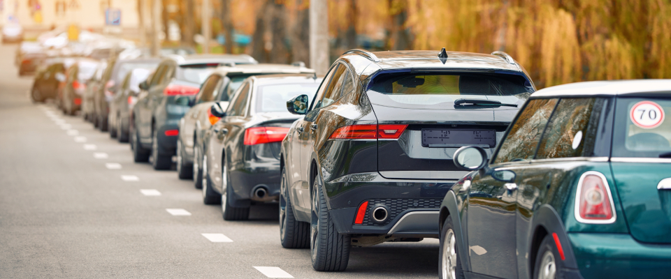 Row of cars parked along a city street—highlighting the importance of asking about off-street parking and residential permit rules before renting apartments in Albany, NY.