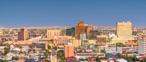 Aerial view of downtown El Paso, Texas at dusk, featuring city lights, apartment buildings and surrounding affordable neighborhoods with budget-friendly rentals.