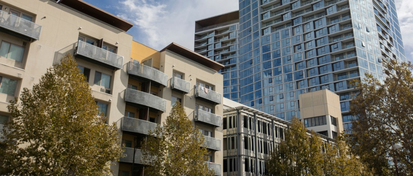 Modern mid-rise and high-rise apartment buildings in San Jose, CA, surrounded by trees, representing affordable neighborhoods with rental housing options in the city.