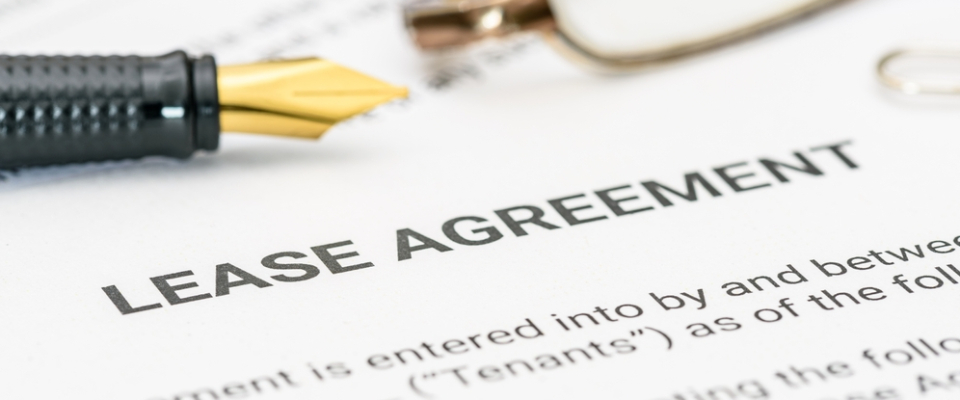Close-up of a lease agreement document on a desk with a pen nearby, representing the paperwork involved in reviewing or signing a lease extension.