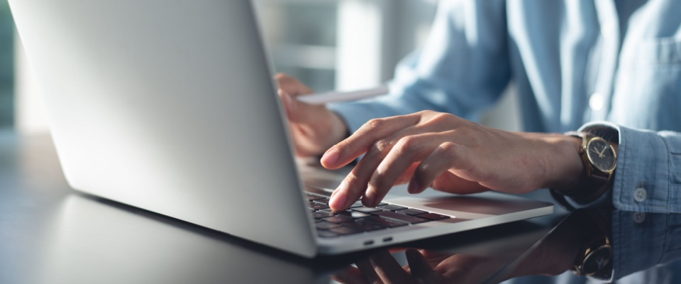 A woman texting on a laptop to illustrate ways to submit a maintenance request.