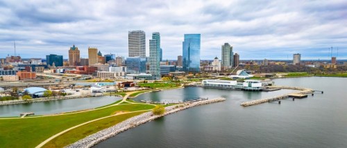 New apartments in Milwaukee highlighted by the city skyline with modern skyscrapers viewed from Lakeshore State Park along Lake Michigan.
