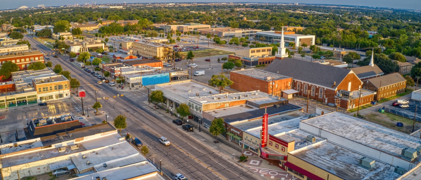 New apartments in Arlington highlighted by an aerial summer view of the surrounding DFW suburb landscape near Grand Prairie, Texas.